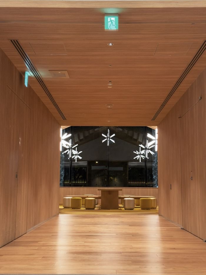A sleek modern hallway with wooden paneling, star-shaped lights, and an exit sign.